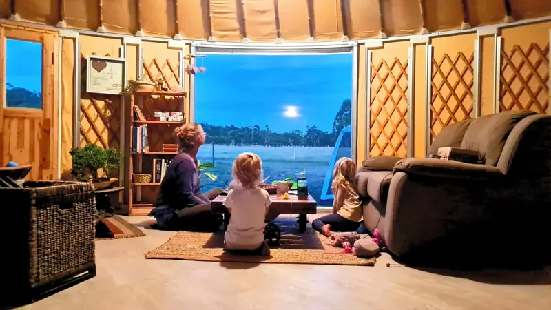 a family at a yurt window watching the full moon