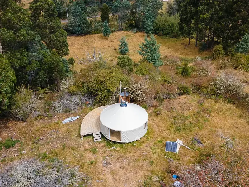 Round yurt interior with lattice walls, a wood heater and a mezzanine
