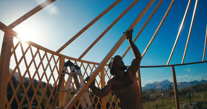 Roof rafters going in, with the installer silhouetted against the sun and mountains