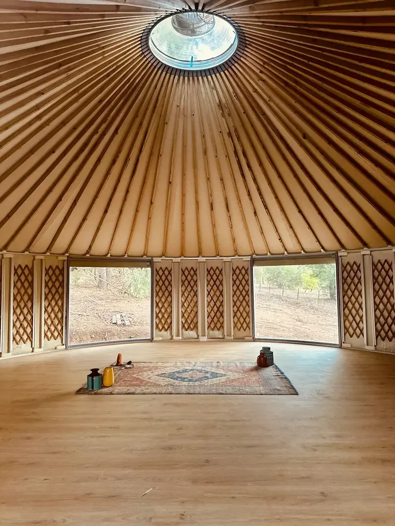 Round yurt interior with a sofa, dining table and lattice walls