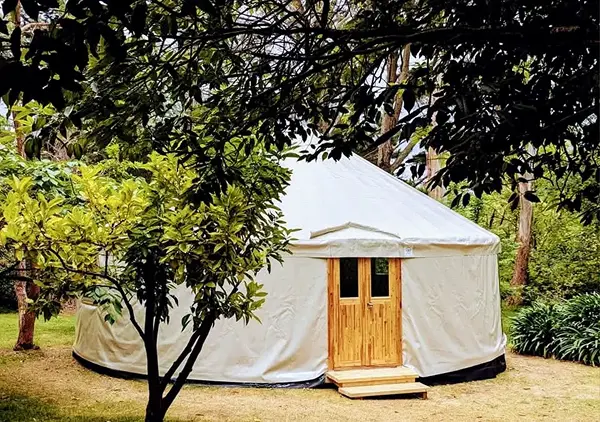 Furnished yurt interior with lattice walls, a bed and large windows
